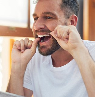 Man smiling while flossing his teeth