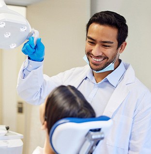 Dentist pulling lights closer to examine woman’s mouth