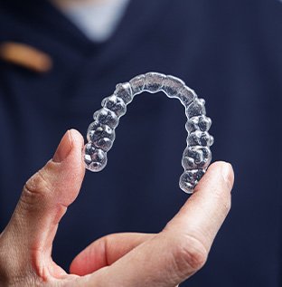 Man in navy scrubs holding Invisalign tray