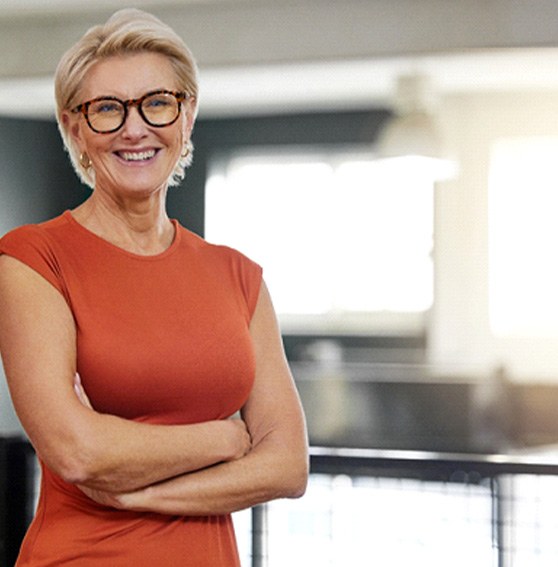 Senior woman with glasses smiling with arms folded