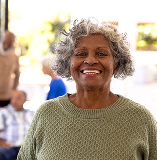 Senior woman in green shirt smiling with people in background