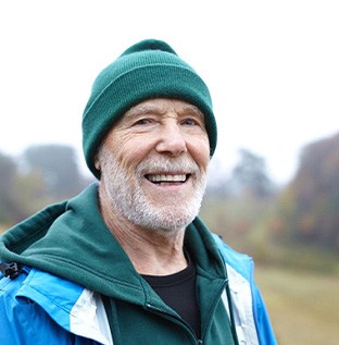 Bearded senior man standing outside and smiling