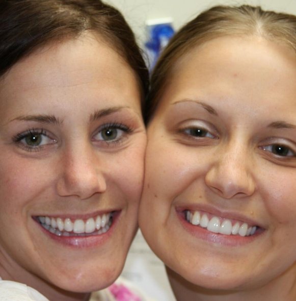 Two women with healthy smiles after receiving comprehensive dental care for patients of all ages