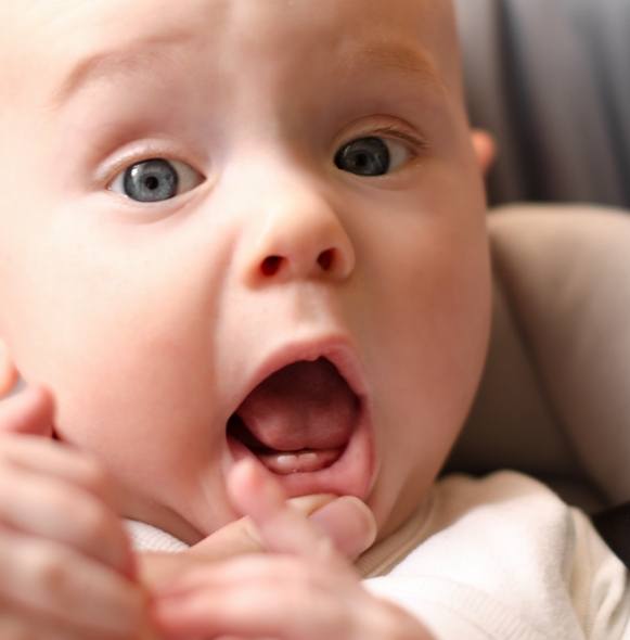 Mother helping baby stretch before feeding as part of frenectomy post op care