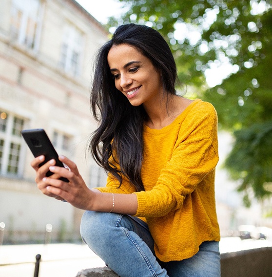 Woman with dental implants in Kittanning, PA checking her phone