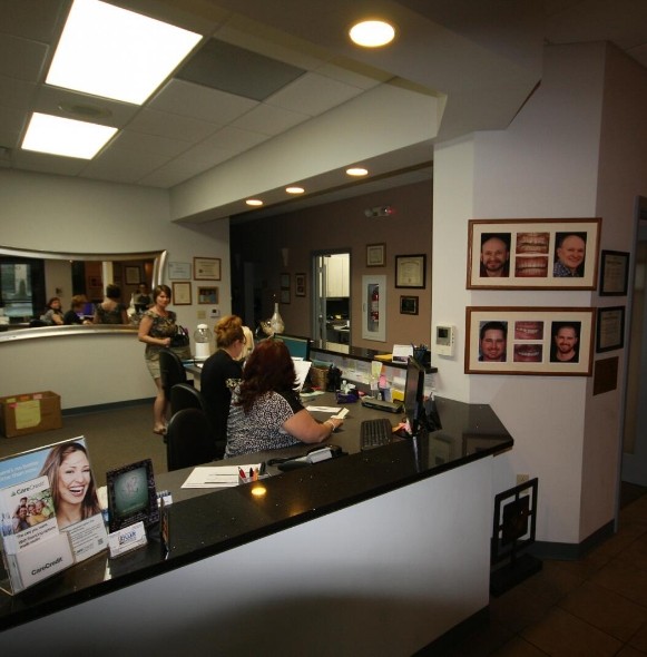 Dental team members behind reception desk prepared to help you understand the cost of dental implants