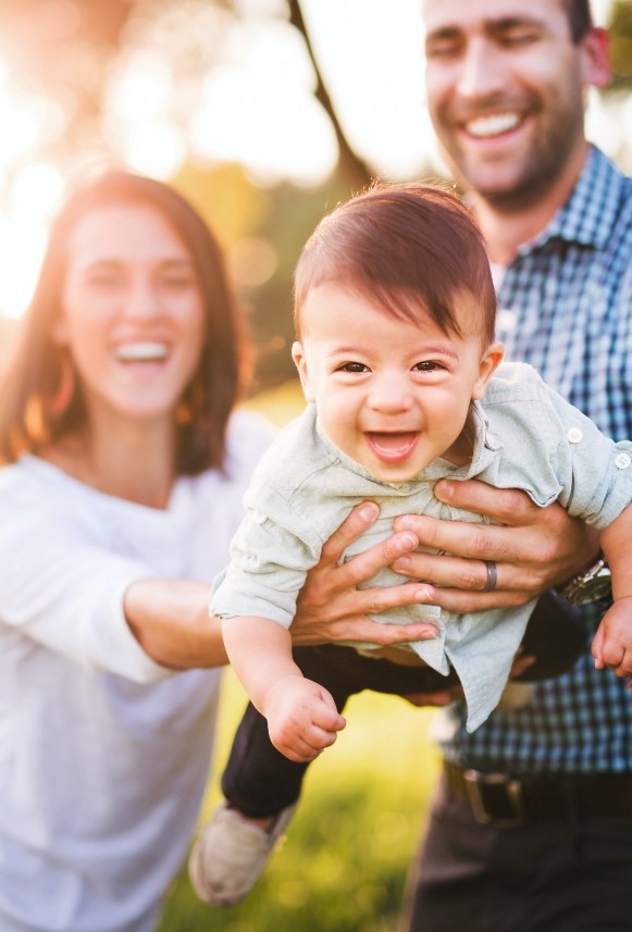 Parents holding laughing baby after lip and tongue tie treatment