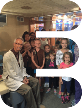 Dentist smiling with group of dental patients shaped like the letter E