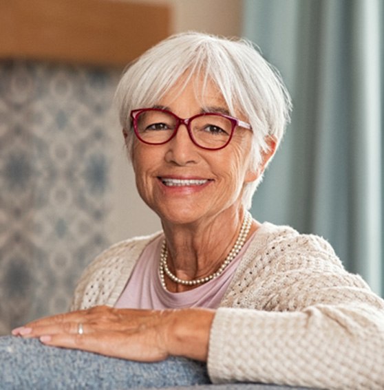 Smiling senior woman with glasses sitting on couch