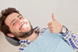 man smiling while receiving dental checkup
