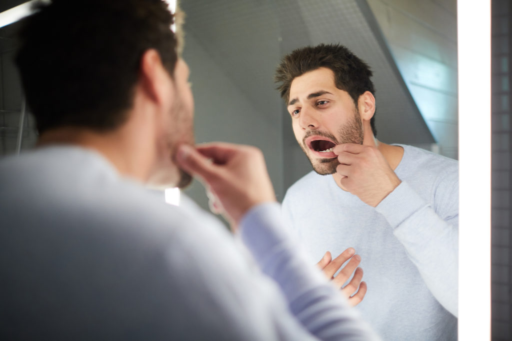 Man checking his dental crown in the mirror