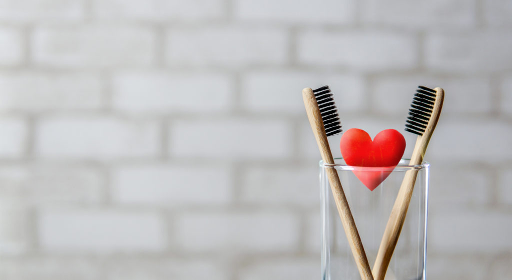 Two toothbrushes and a heart in a clear cup