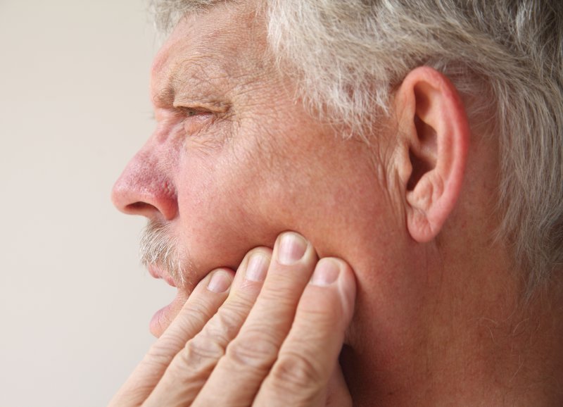 Man rubbing jaw in pain looking concerned