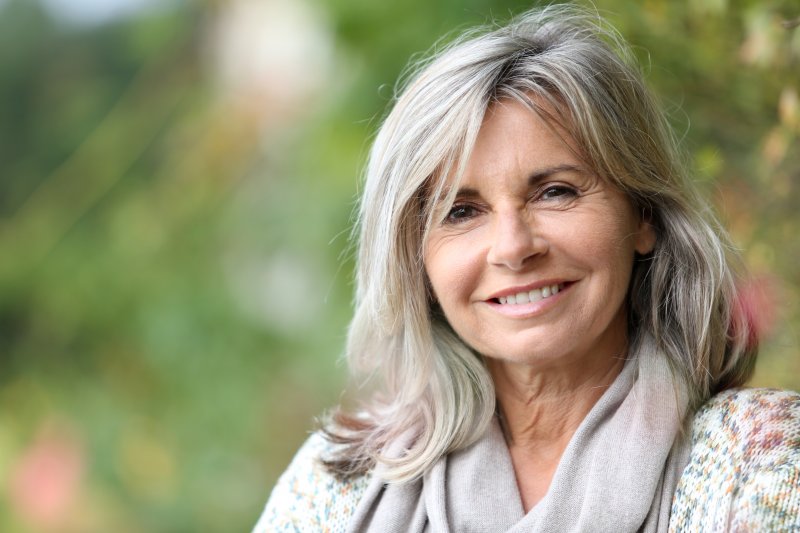 Older woman in sweater sitting outside with dentures