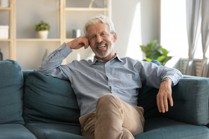 Senior man leaning back on couch and smiling