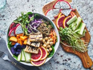 Vegetables, fruits, and sprouts in bowl and on cutting board