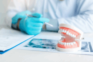 Dentist sitting at desk with a model set of dentures and an X-ray