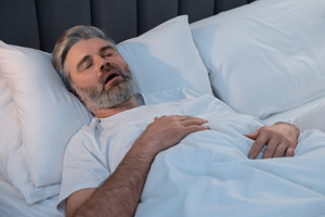 Bearded man lying in bed and snoring